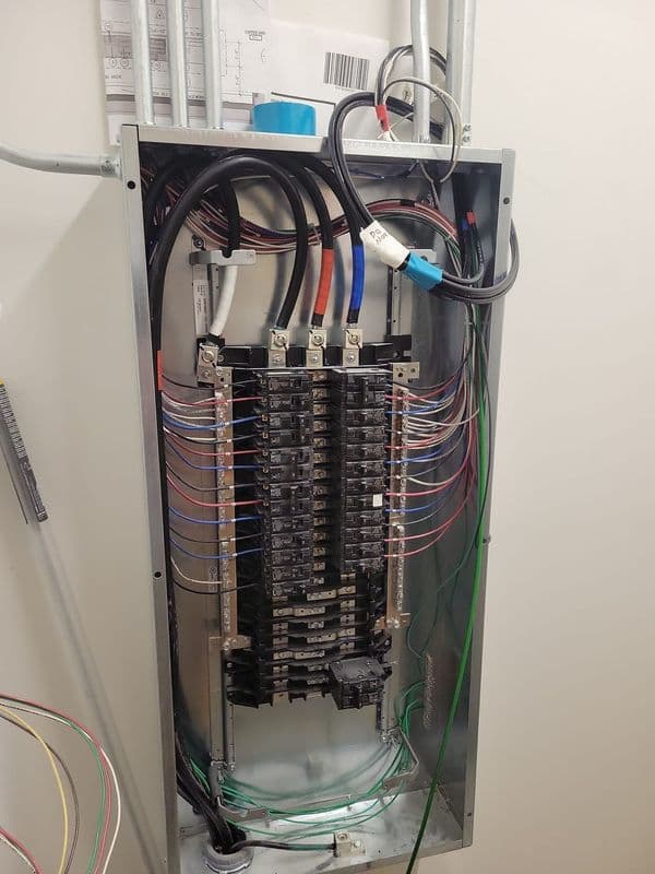 Electrical panel with circuit breakers and wiring in a residential setting.