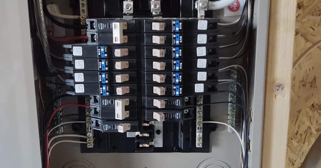 Electrical circuit breaker panel with multiple breakers and wiring connections.