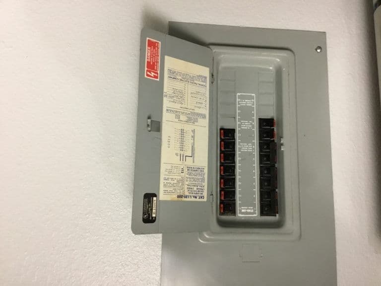 Electrical panel with open breaker box displaying circuit labels for safety and maintenance.