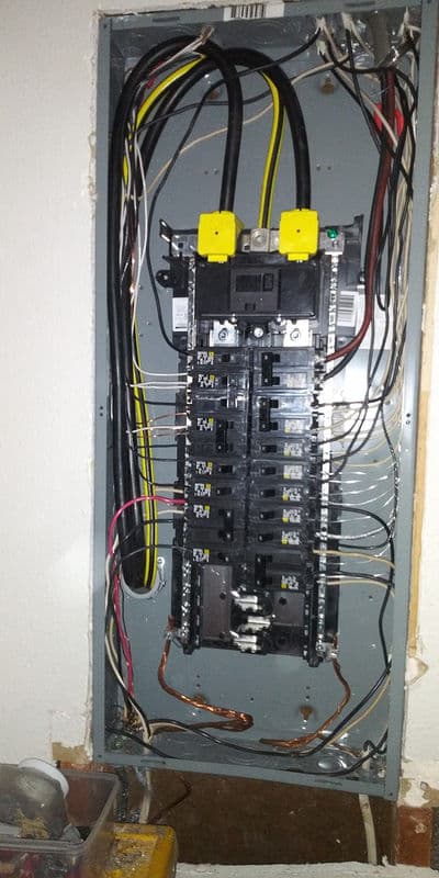 Electrical panel with multiple circuit breakers and wiring, displaying typical residential setup.