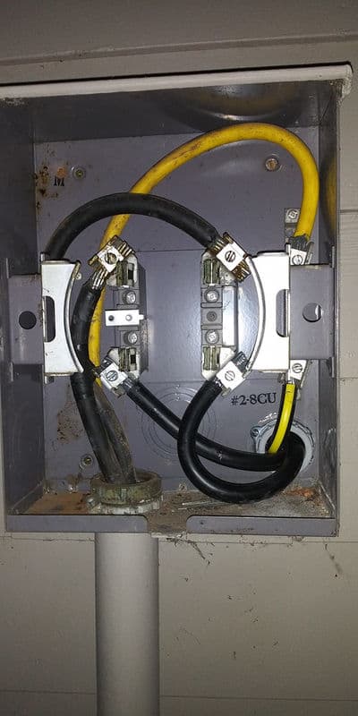 Electrical junction box with yellow and black wires connected to copper terminals.