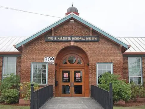 Red brick entrance of the Paul H. Karshner Memorial Museum with arched wooden doors and a small cupola