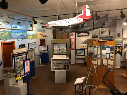 Indoor aircraft museum with a model plane hanging from the ceiling and display cases at McChord Air Museum